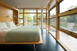 King bed facing windows with wood frames in bedroom with view of backyard deck