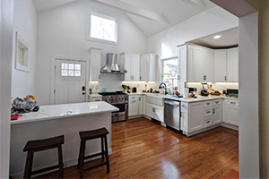 Remodeled kitchen with white cabinets, marble countertops, and natural wood flooring